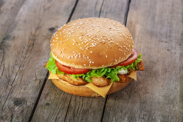 hamburger with chicken and cheese on a wooden surface