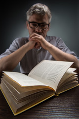 Man sitting at brown table and reading book.