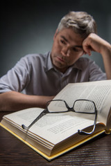 Man sitting at brown table and reading book.