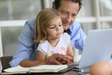 Man with daughter looking at internet on laptop