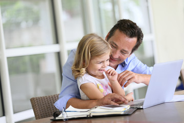 Fototapeta na wymiar Man with daughter looking at internet on laptop