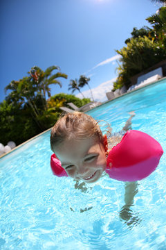 Cheerful little girl in swimming-pool