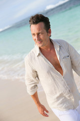 Fototapeta na wymiar Handsome 40-year-old man walking on beach