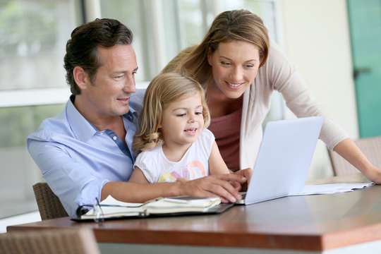 Parents with little girl looking at pictures on computer