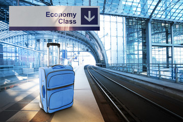 Economy Class. Blue suitcase at the railway station
