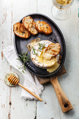 Baked Camembert cheese with toasted bread on cast-iron frying pa