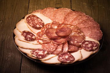 Obraz premium plate with different sliced sausage on an old wooden table