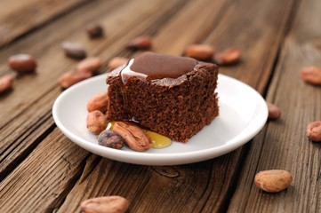 Chocolate cake with cocoa beans and honey on wooden background