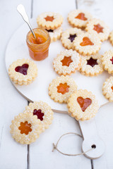 Weihnachtsplätzchen mit Konfitüre auf einem Holzbrett