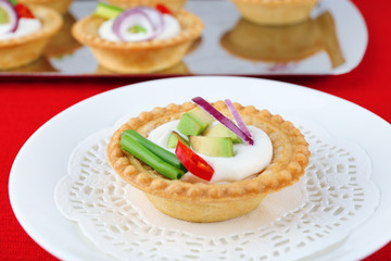 Tartlets with greens and vegetables with sauce on plate and
