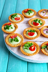 Tartlets with greens and vegetables with sauce on tray on table