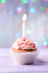 Delicious birthday cupcake on table on light background