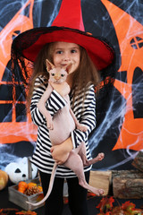 Little girl Witch with cat on Halloween decorations background