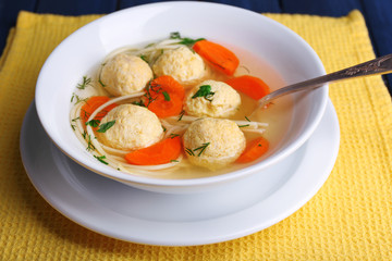 Soup with meatballs and noodles in bowl on wooden background