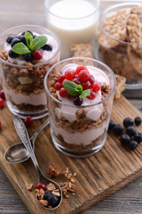 Healthy layered dessert with muesli and berries on table
