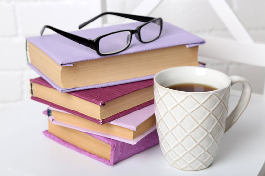 Pile of books with cup and glasses