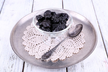 Metal tray with glass bowl of prunes, lace doily and spoon