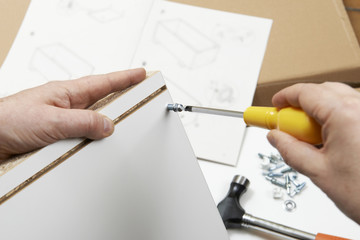Close Up Of Man Assembling Flat Pack Furniture With Screwdriver