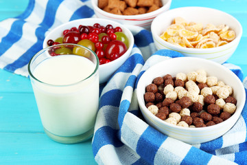 Various sweet cereals and berries in ceramic bowls and glass