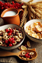 Various sweet cereals in ceramic bowls, fruits and jug with
