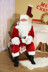 Santa Claus sitting in comfortable chair near fireplace at home