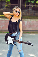 Beautiful hipster girl in sunglasses with electric guitar