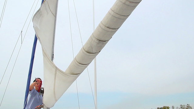 Positive girl sailor lifting the sail on yacht, tourism, travel