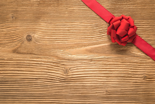 Red ribbon and bow over wooden background