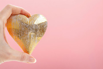 Woman holding golden heart, pink background