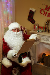 Santa Claus sitting with list of presents in comfortable chair