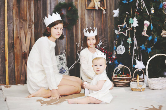 Three sisters posing in front of christmas tree