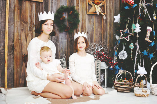 Three sisters posing in front of christmas tree