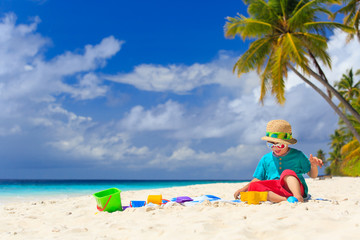 Fototapeta na wymiar little boy building sand castle on beach