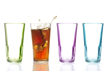 Drei leere bunte Trinkgläser und ein gefülltes Glas