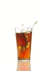 Eiswürfel fällt in Glas mit Cola vor weißem Hintergrund