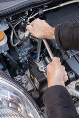 Mani che riparano um motore di automobile con una chiave