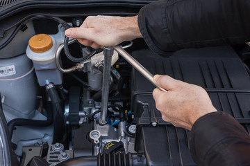 Mani che riparano um motore di automobile con una chiave