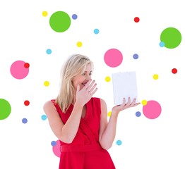 Composite image of stylish blonde in red dress holding gift bag