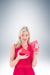 Stylish blonde in red dress opening gift box