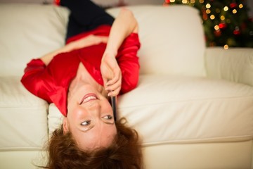 Happy redhead lying on the couch phoning