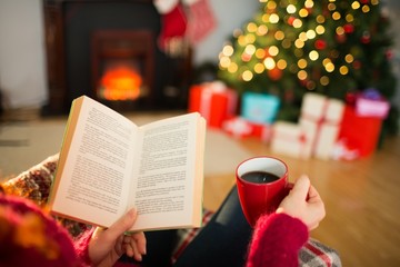 Woman reading a book and drinking coffee at christmas