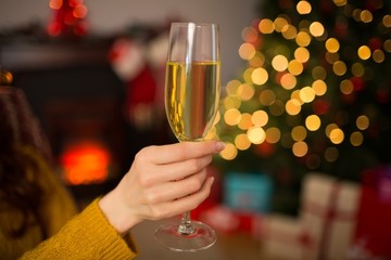Redhead holding glass of champagne on couch at christmas