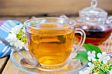 Tea from flowers of viburnum on wooden board with napkin