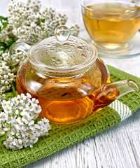 Tea with yarrow in glass teapot on board © kostrez