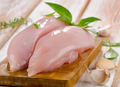Raw chicken breast fillets on  cutting board.