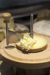 Tete de moine raw milk cheese to be cut on wooden tray