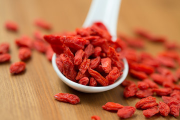 dried goji berries in white spoon on wooden table
