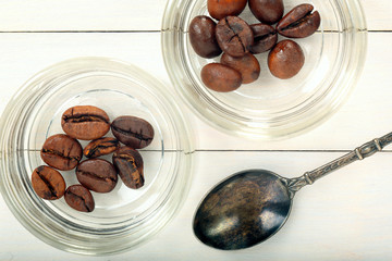 Coffee beans in glass jars with vintage spoon on wooden backgrou