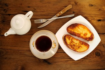 Two white toasts on white plate with cup of black tea