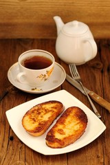 Two white toasts on white plate with cup of black tea